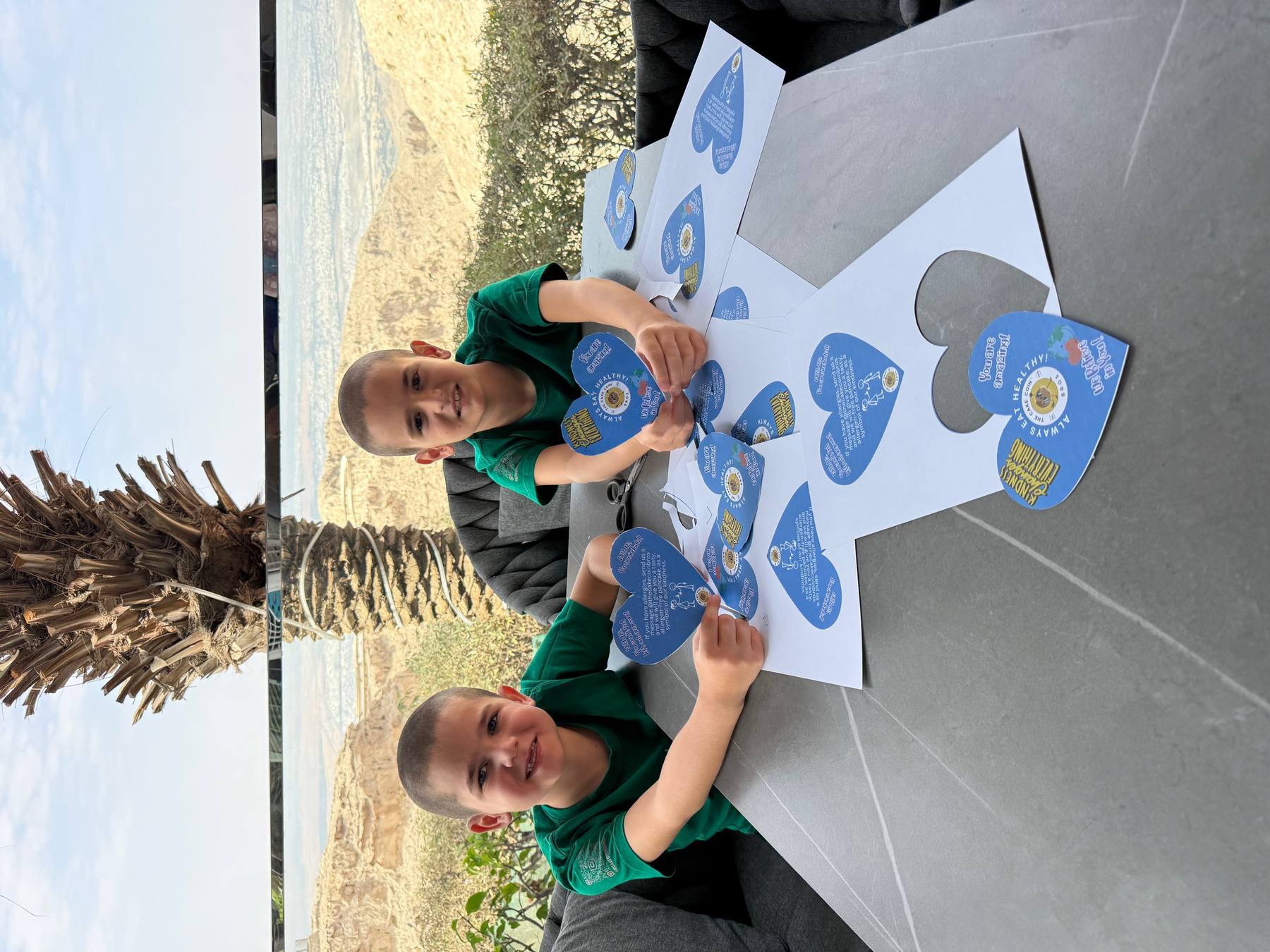 Aaron and Nathan with blue paper hearts from the UAE Kindness Campaign